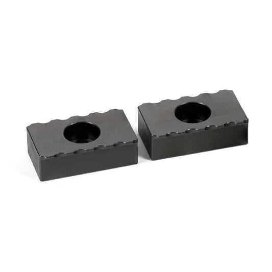Two black serrated grippers with a central hole, designed for tooling and workholding in manufacturing.