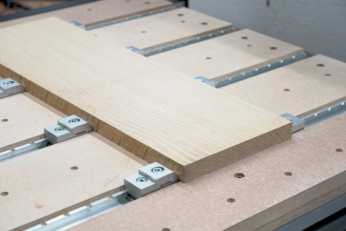 T-track clamp holding a board of white oak on a cnc router